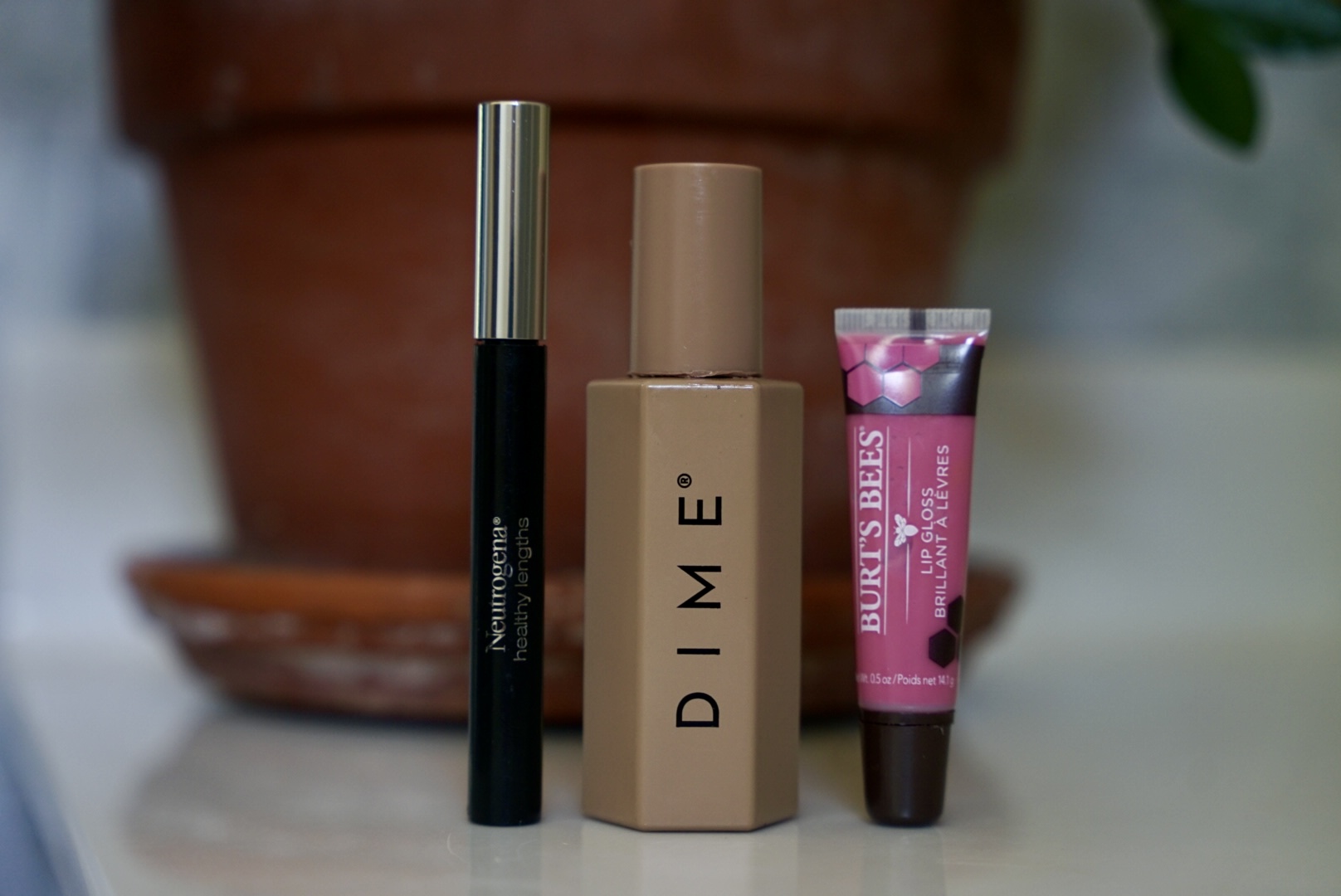 Flat lay of everyday no-makeup makeup essentials including tinted SPF, brow gel, cream blush, and lip balm—perfect for busy moms and natural summer beauty routines.