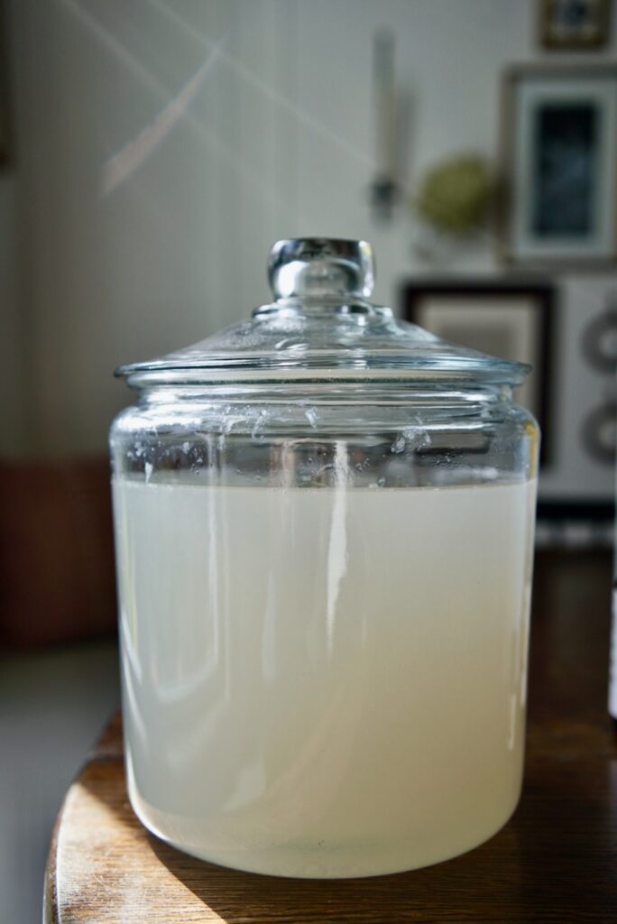 Mixing borax, washing soda, and castile soap in a pot to create homemade liquid laundry detergent.
