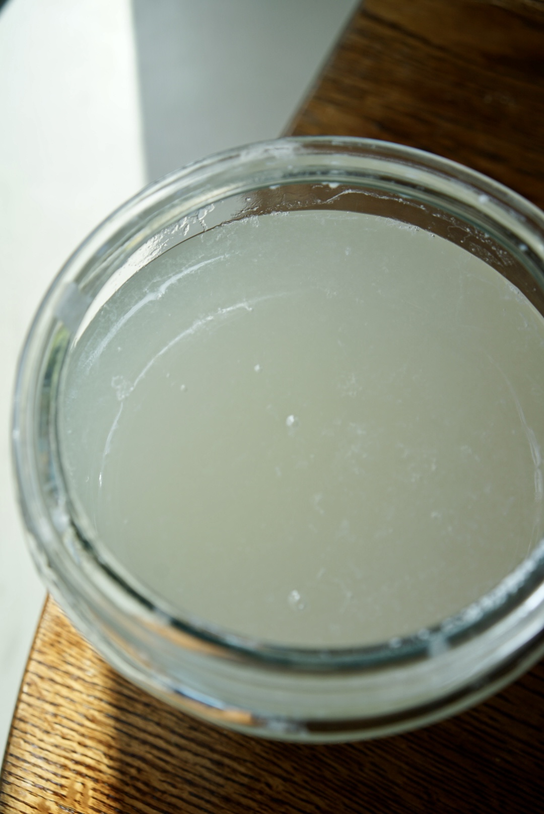 Gallon glass container filled with homemade laundry detergent made from borax, washing soda, castile soap, and essential oils, ready to use
